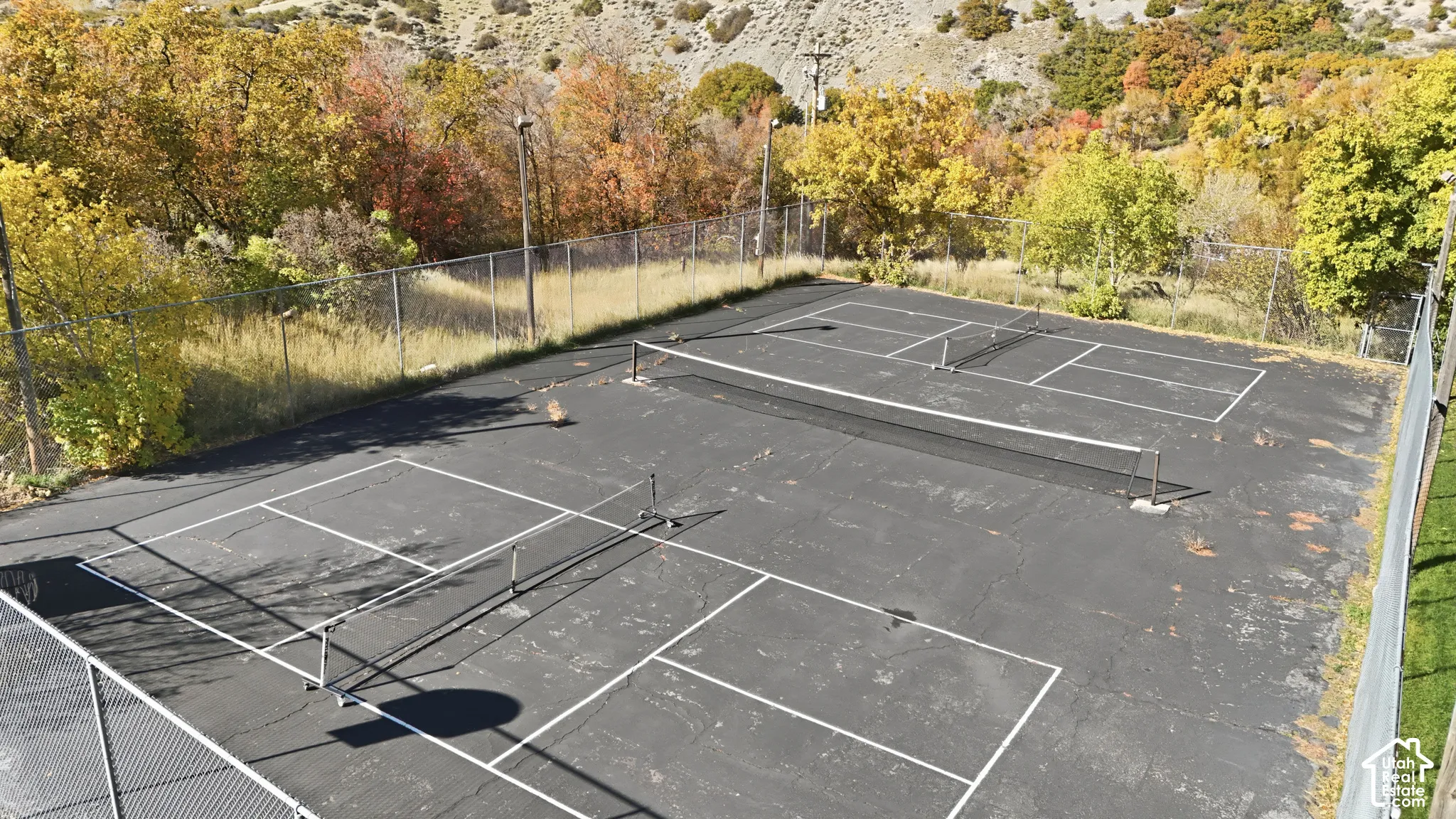 Dual-court surface with perimeter chain-link fencing and elevated pole-mounted lighting