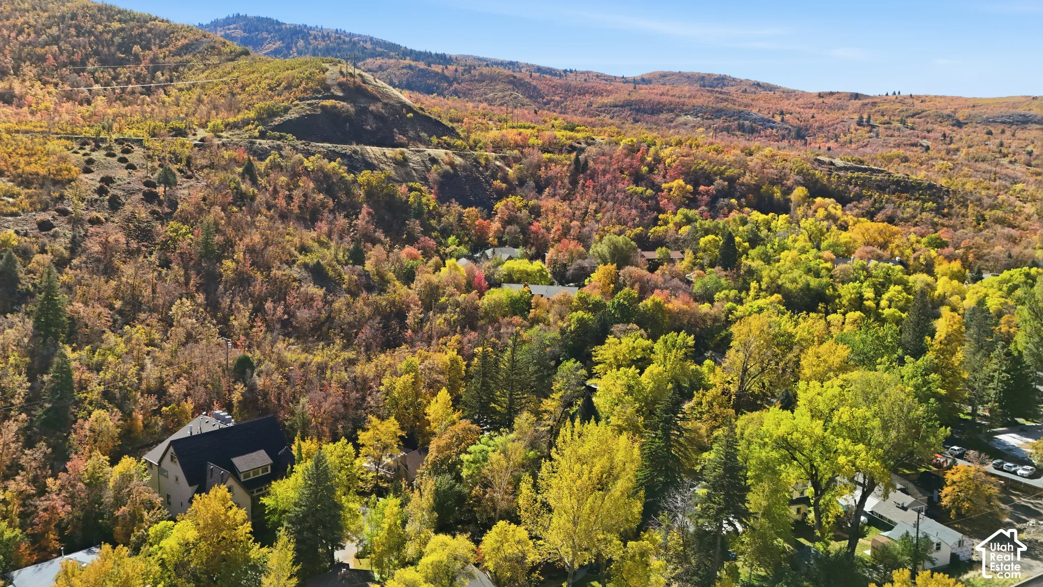Aerial perspective of a multi-story residence surrounded by dense foliage and rugged mountain terrain