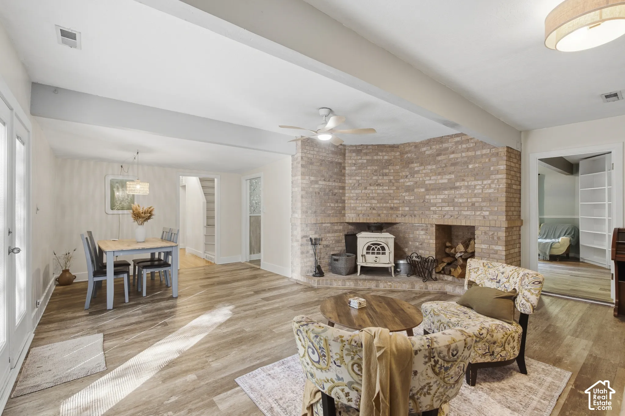 Living area featuring wood-finish flooring, a corner brick fireplace with a hearth