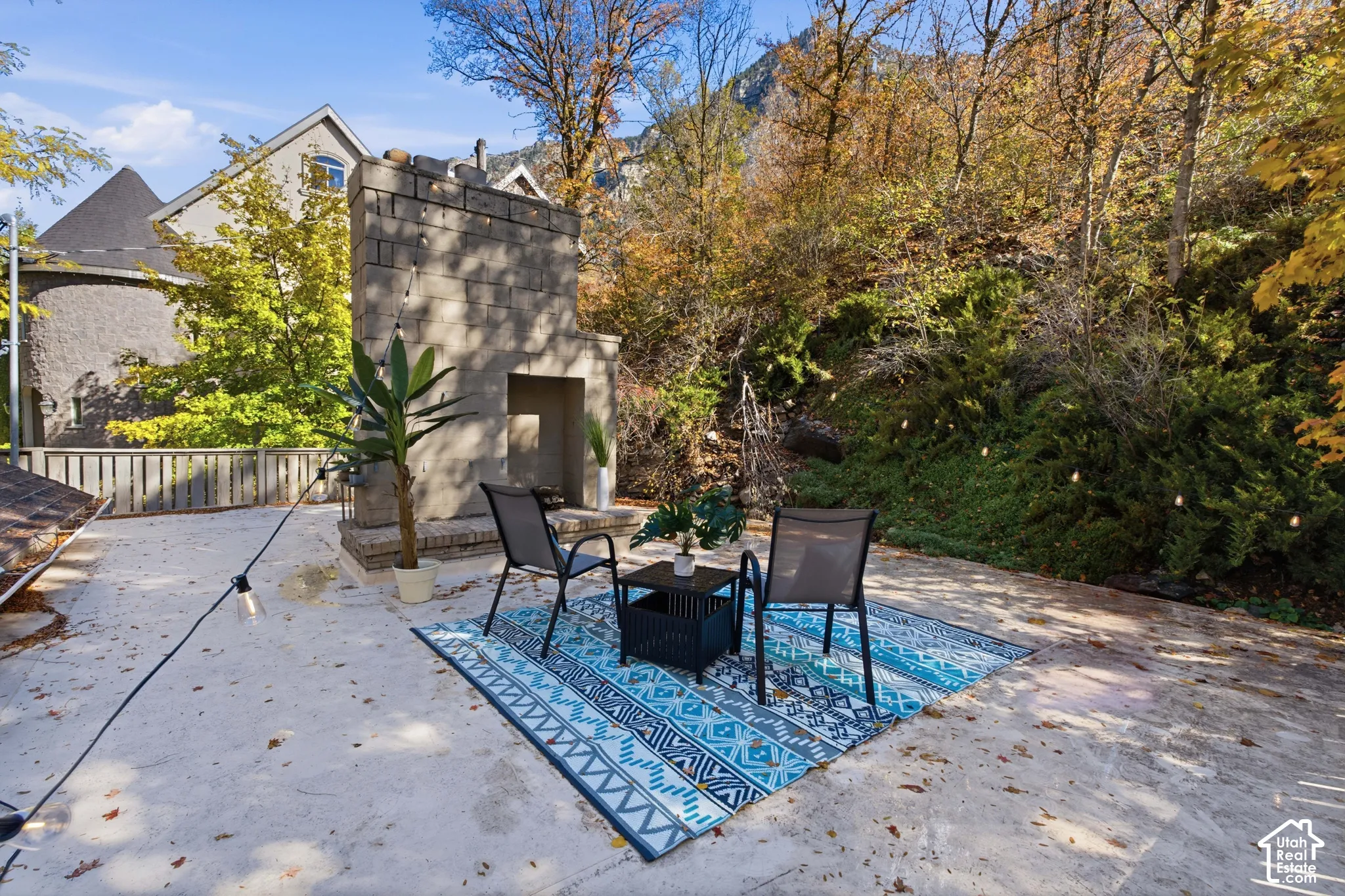 Upstairs terrace deck featuring a stone fireplace, wood-slat fencing, and a natural, wooded mountain backdrop