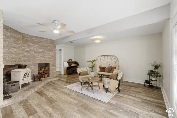 Second living room featuring wood-finish flooring, a floor-to-ceiling brick fireplace with wood burning stove