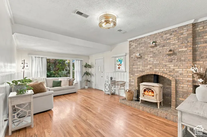 Living area, front room featuring wood-finish flooring, a floor-to-ceiling brick fireplace with wood burning stove