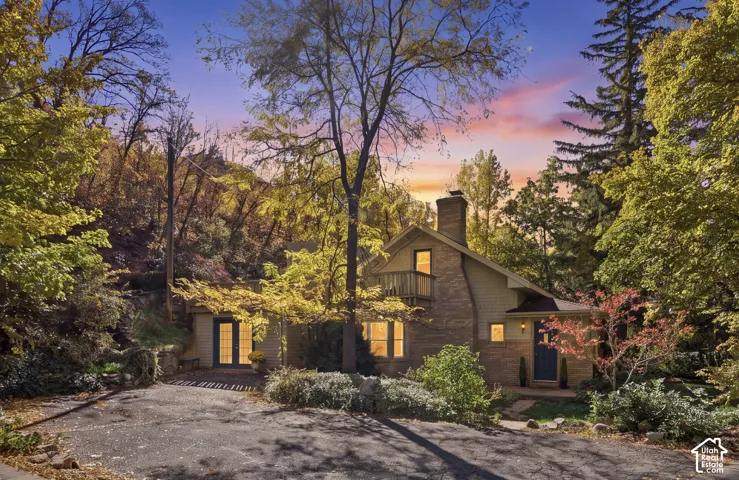 Exterior facade with a chimney, a private balcony, and mature surrounding landscape
