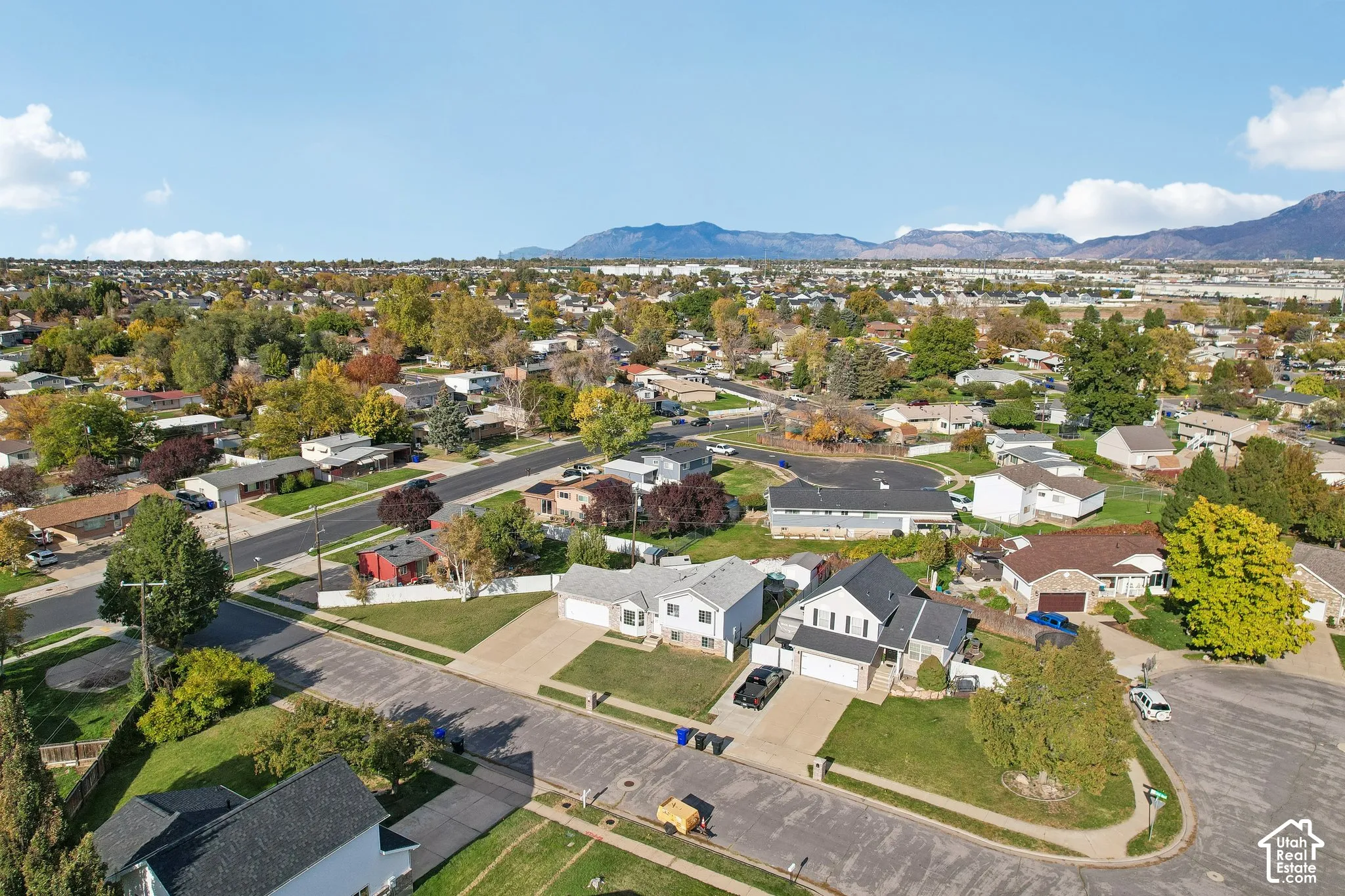 Aerial perspective of a suburban neighborhood featuring residential lots, paved streets, and a mountainous backdrop