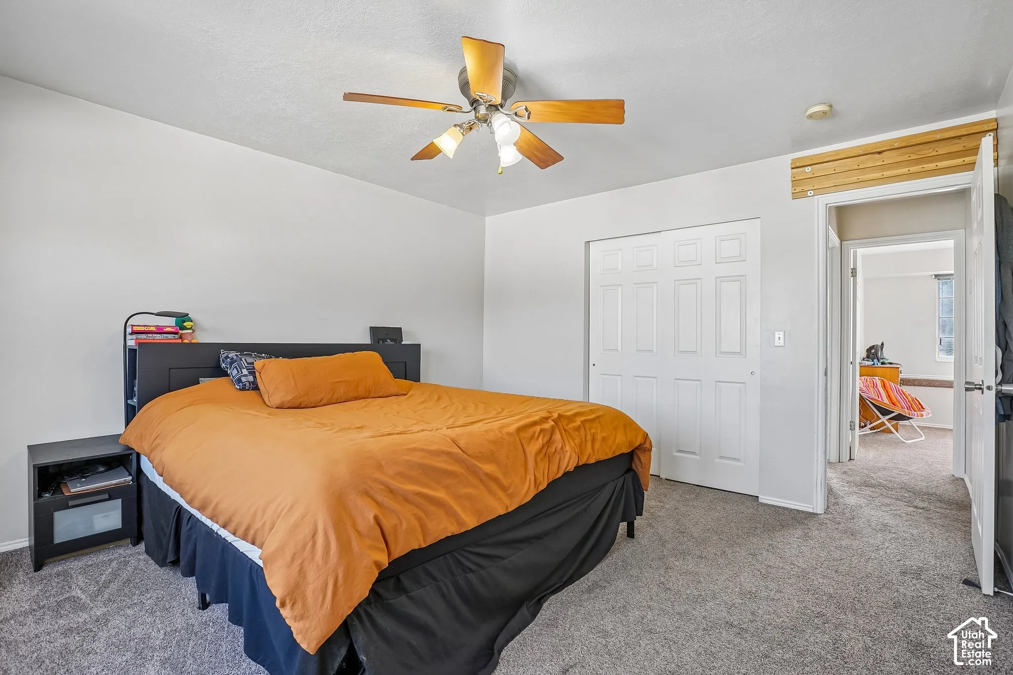 Neutral wall-to-wall carpeting, ceiling fan with integrated lighting, and dual-panel sliding closet doors