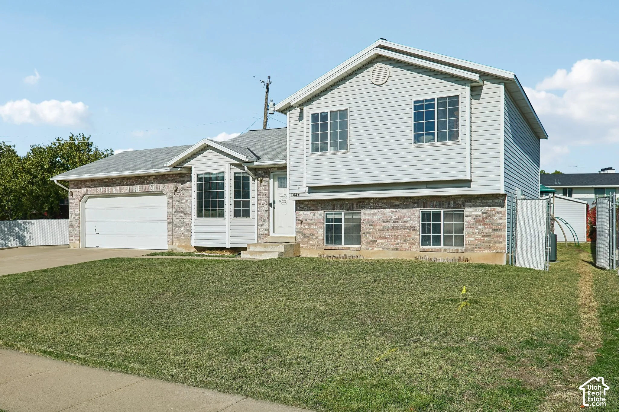 Multi-level exterior featuring a combination of brick masonry and horizontal siding, an attached two-car garage, and double-pane windows