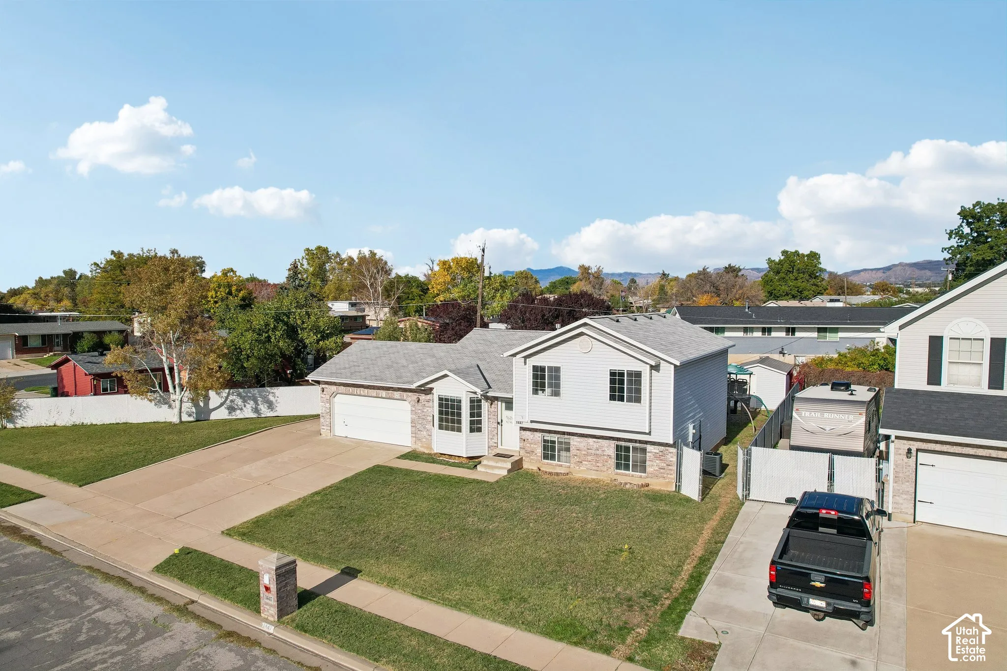 Split-level exterior featuring a combination of brick and horizontal siding, an attached two-car garage, a bay window, and a concrete driveway