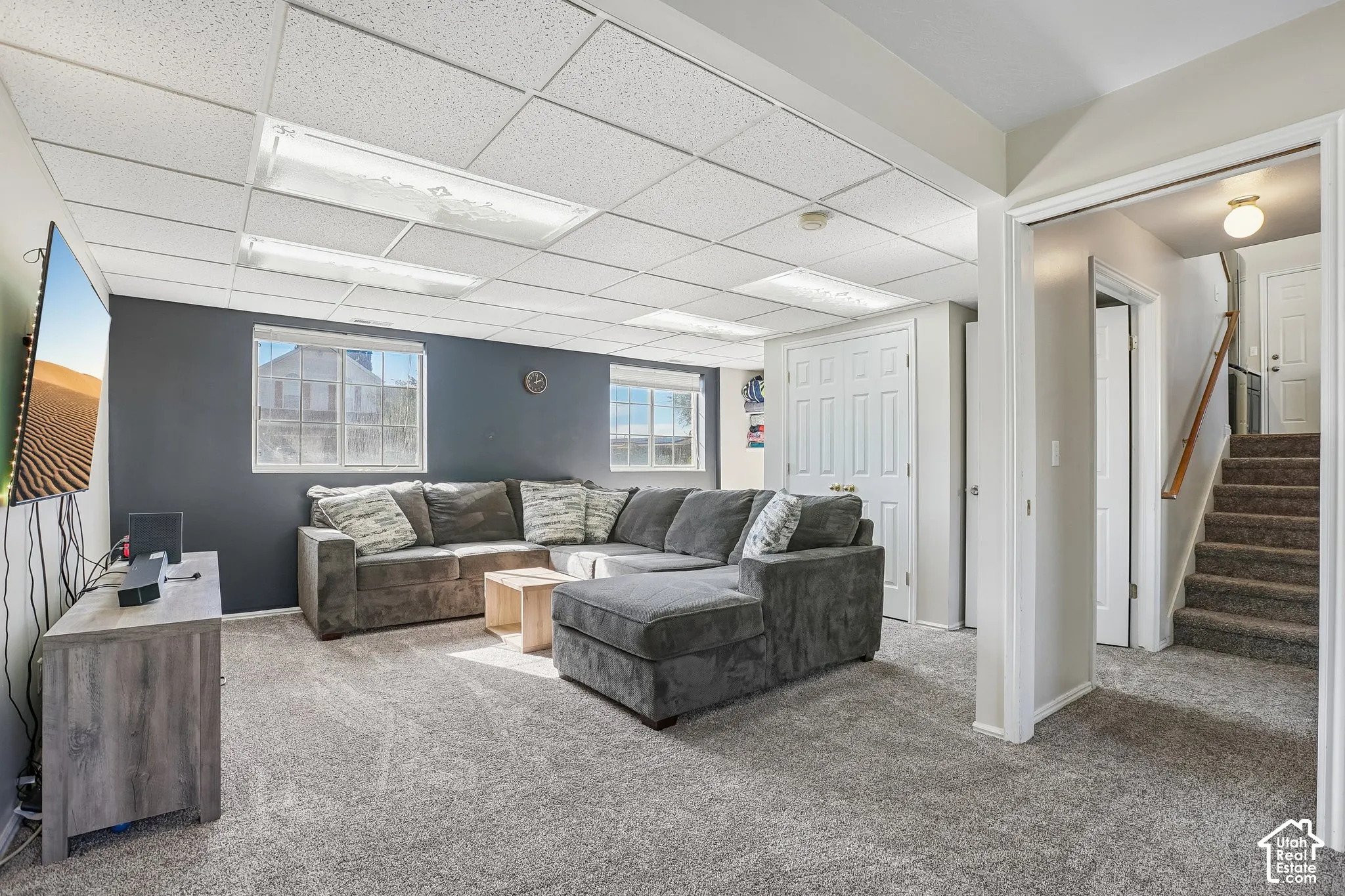 Finished room featuring a drop ceiling with recessed lighting, neutral carpeting, and a dual-panel closet
