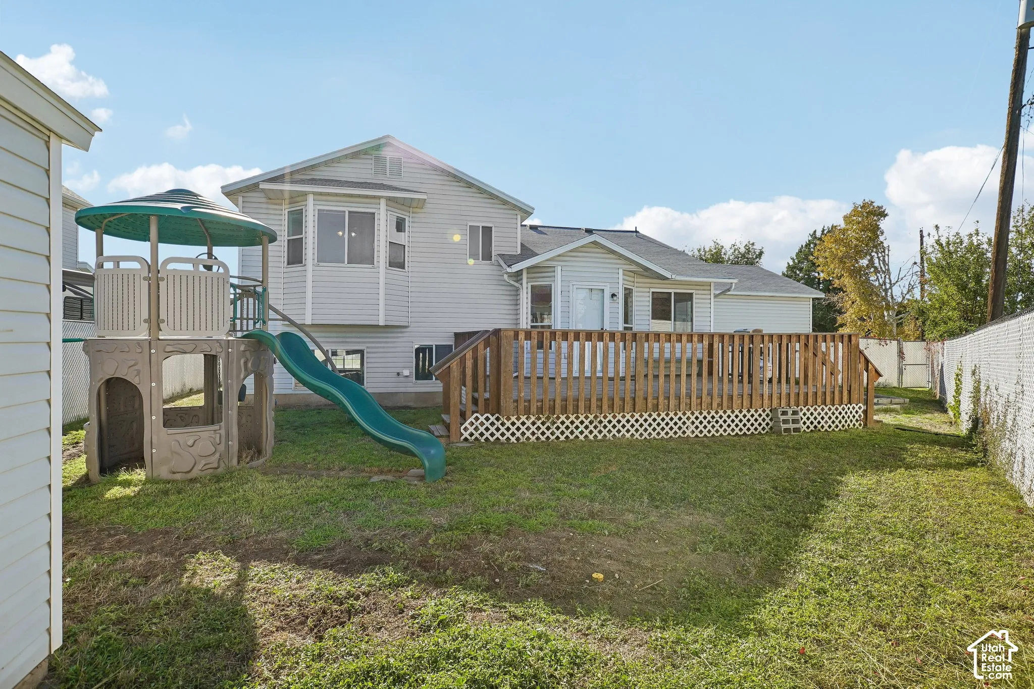 Exterior featuring vinyl siding, elevated wood deck with lattice skirting, and fenced perimeter