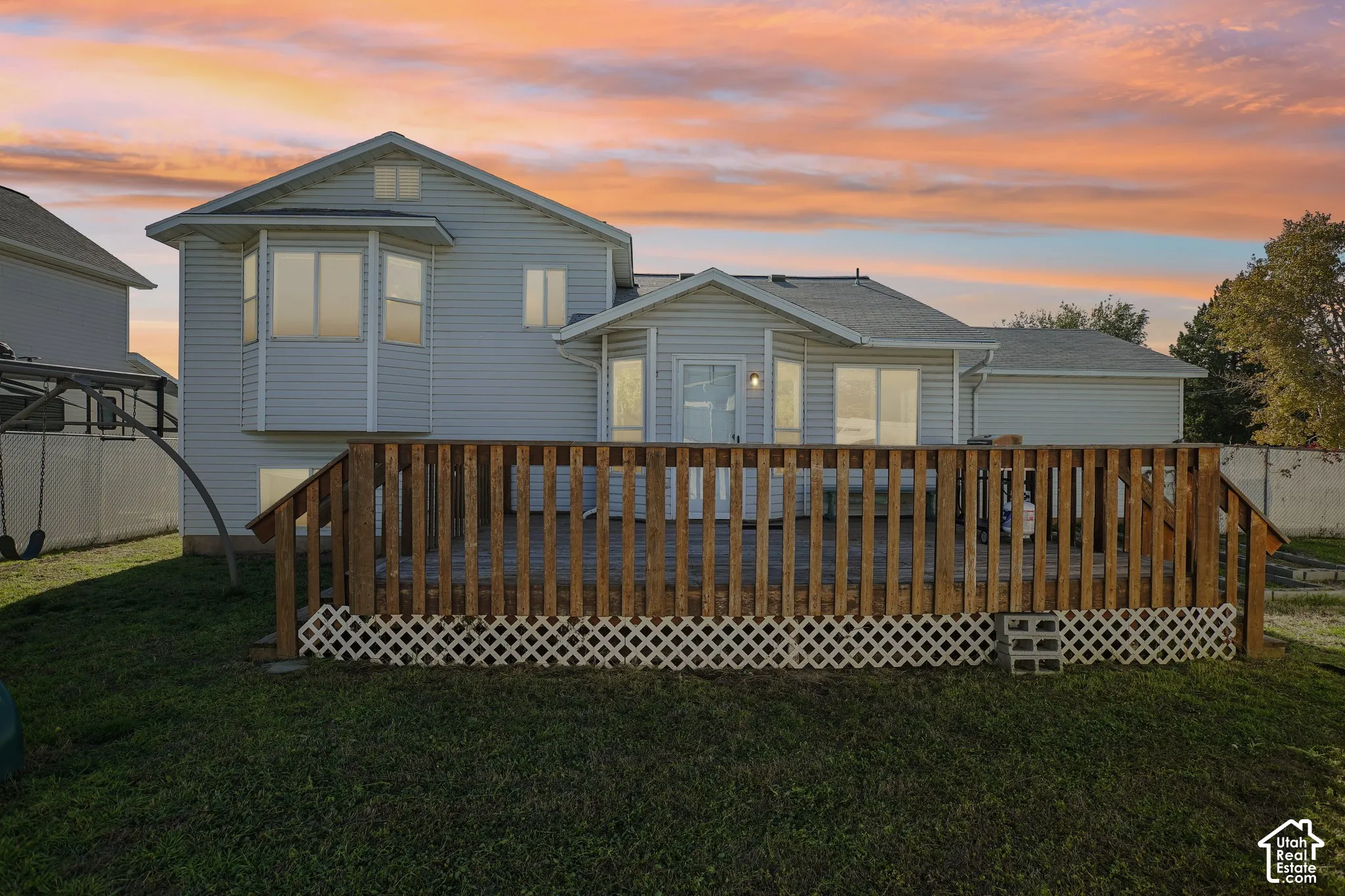 Multi-level exterior featuring horizontal siding, a raised wood deck with balustrades, lattice skirting, and multiple bay windows