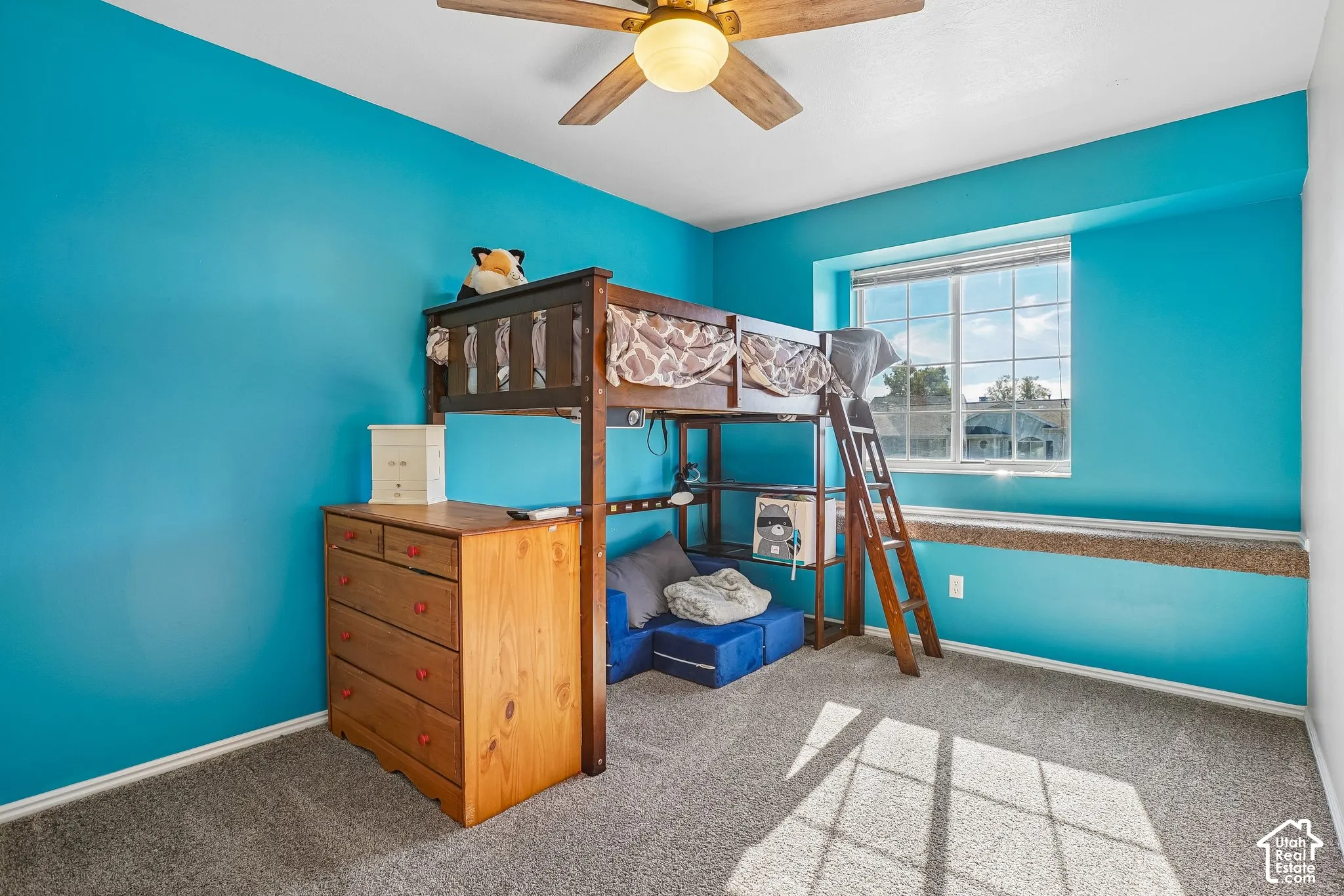 Room featuring wall-to-wall carpeting, a multi-pane window, integrated carpeted window ledge, and a ceiling fan with light fixture