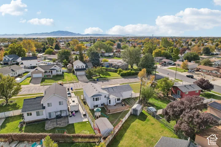 Aerial perspective featuring paved driveways, established landscaping, fenced perimeters, and a distant mountain backdrop