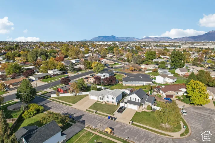 Aerial perspective of a suburban neighborhood featuring residential lots, paved streets, and a mountainous backdrop