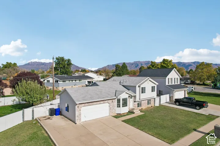 Multi-level residence featuring a stone and siding exterior, two-car garage, concrete driveway, and mountain scenery