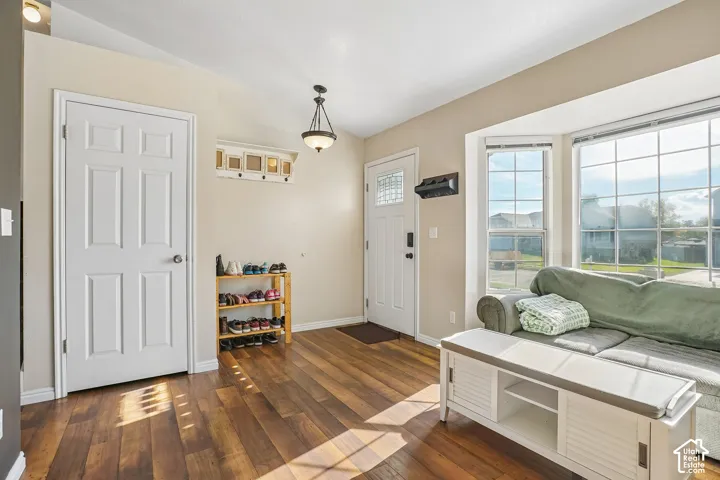 Entryway featuring wood-finish flooring, a bay window with natural light, a six-panel door with a decorative glass insert, and a pendant light fixture
