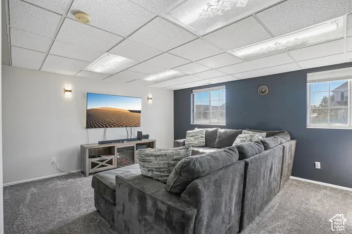 Finished interior space featuring a drop ceiling with integrated lighting, wall-to-wall carpeting, dual wall-mounted light fixtures, and a dual-tone wall finish