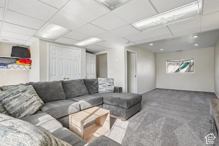 Neutral-toned interior space featuring recessed lighting, a drop ceiling with integrated rectangular light fixtures, carpeting, and double-door closet storage