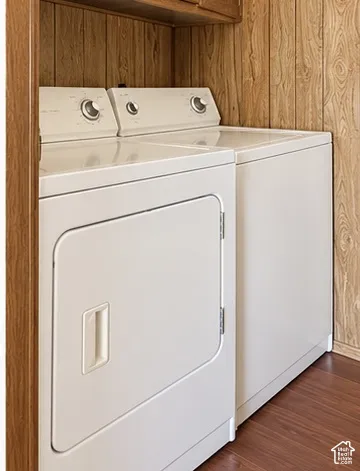 Laundry area featuring wood-paneled walls, wood-finish flooring, and overhead cabinetry