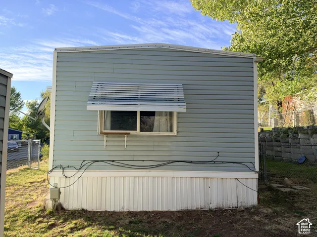 Exterior featuring horizontal light blue siding, white vertical skirting, and a sliding window with a fixed metal awning