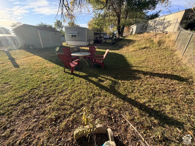 Ground-level outdoor space featuring a detached storage shed, chain-link perimeter fencing, and terraced landscape elements