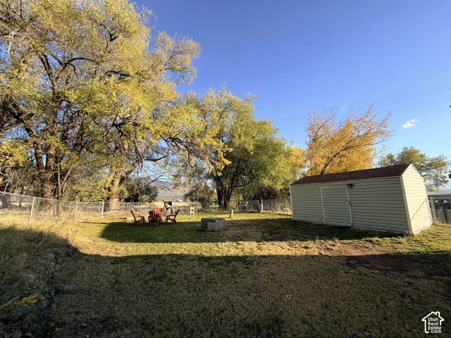 Backyard featuring a detached storage shed, chain-link fencing, and mature trees