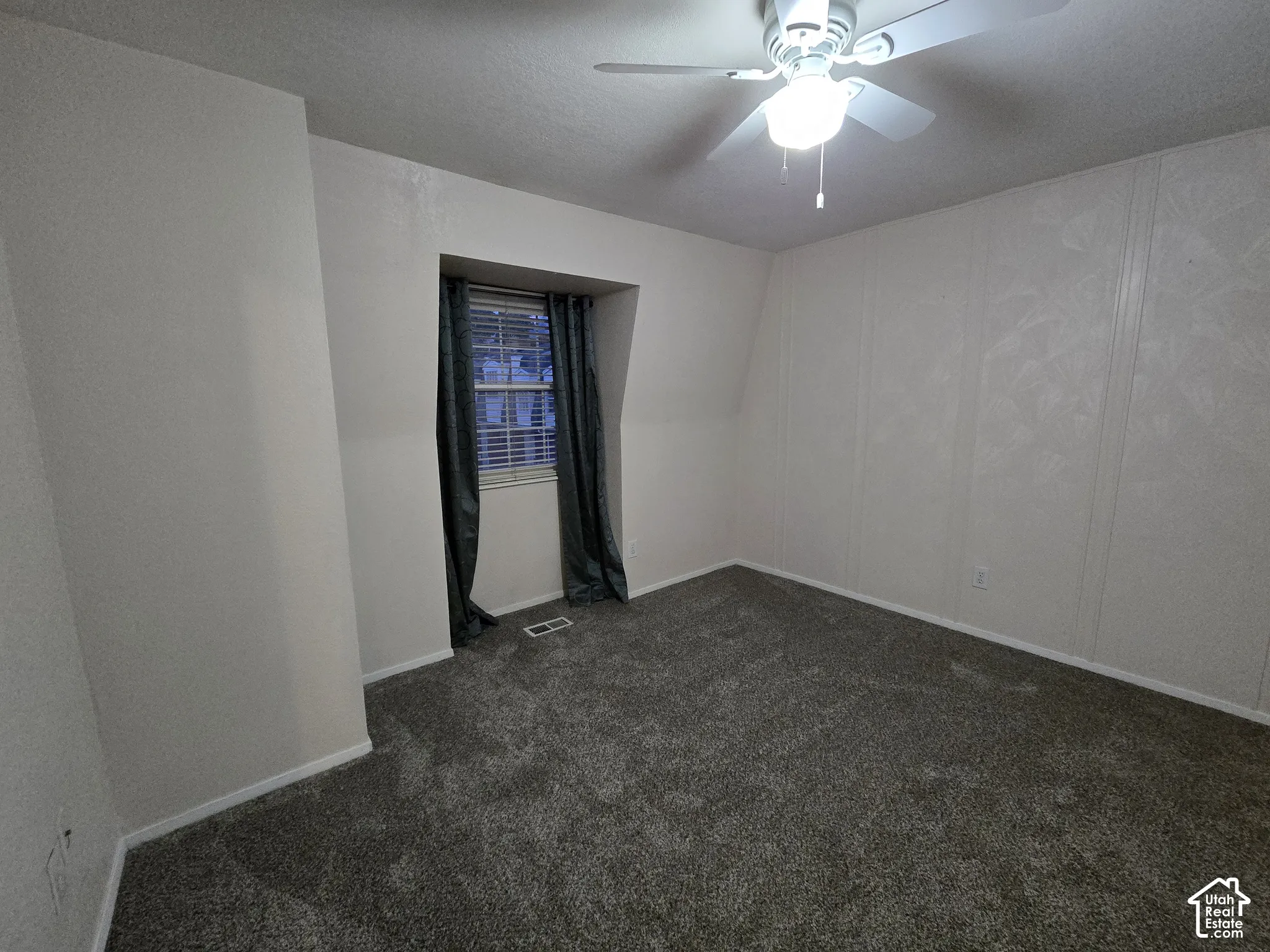 Neutral wall finishes, plush carpeting, a multi-blade ceiling fan with integrated lighting, and a recessed window nook