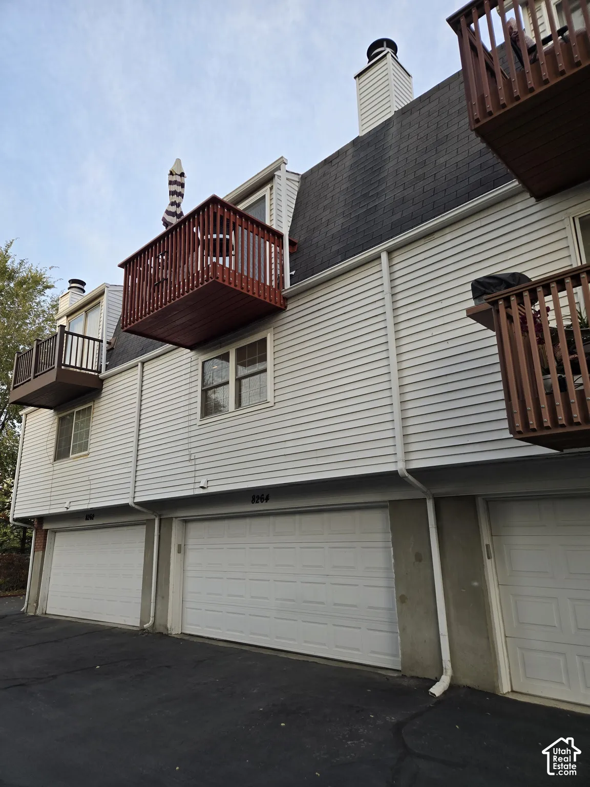 Multi-level exterior featuring horizontal lap siding, multiple private wood-railed balconies, and asphalt shingle roofing with attached garages