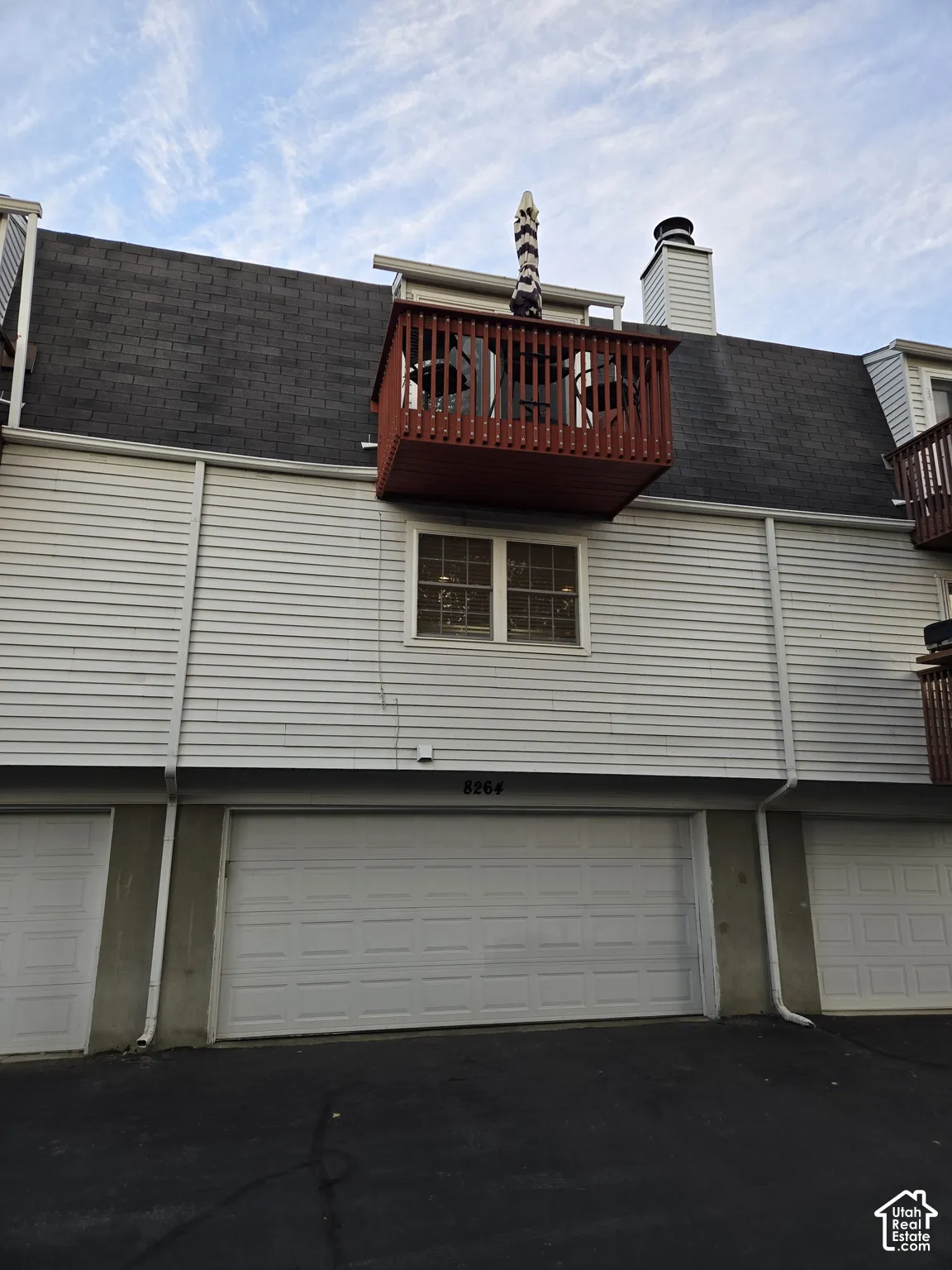 Exterior facade featuring horizontal siding, a private wood-railed balcony, an asphalt shingle roof, and an integrated two-car garage