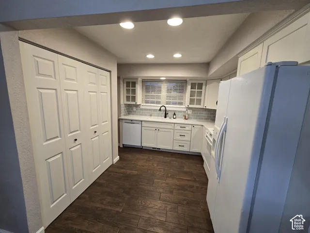 Kitchen featuring wood-finish flooring, white shaker-style cabinetry with glass-panel upper doors, subway tile backsplash, and recessed lighting