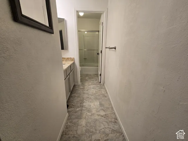Bathroom featuring vanity cabinetry, stone-finish countertop, tile-patterned flooring, and a tub-shower combination with sliding glass doors