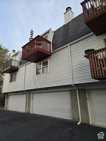 Multi-level exterior featuring horizontal lap siding, multiple private wood-railed balconies, and asphalt shingle roofing with attached garages