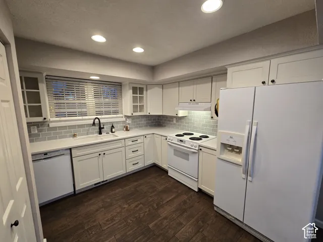 Kitchen featuring white cabinetry, subway tile backsplash, solid-surface countertops, wood-finish flooring, and recessed lighting