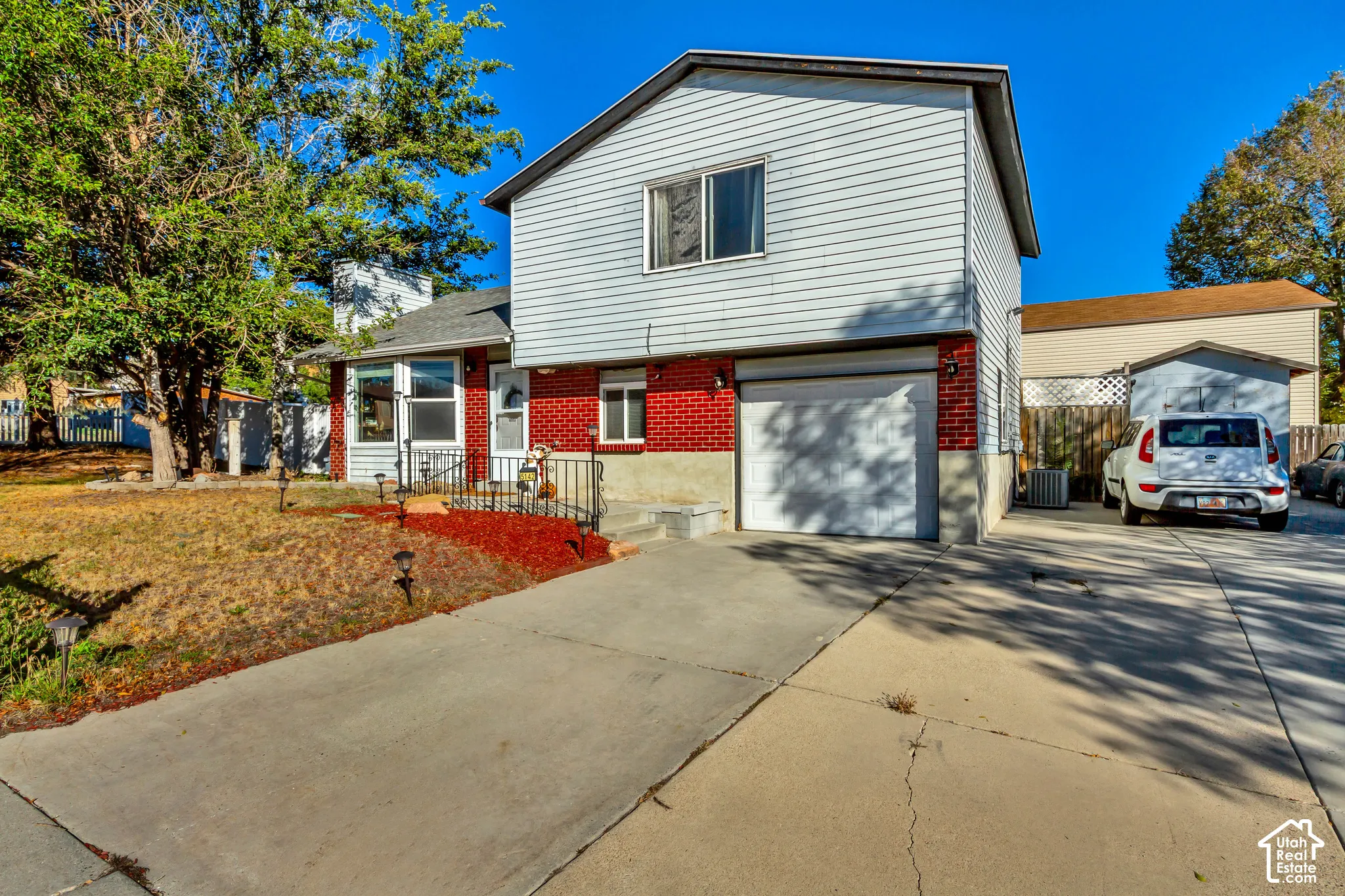 Split-level exterior featuring brick and horizontal siding, an attached single-car garage, and an expansive concrete driveway