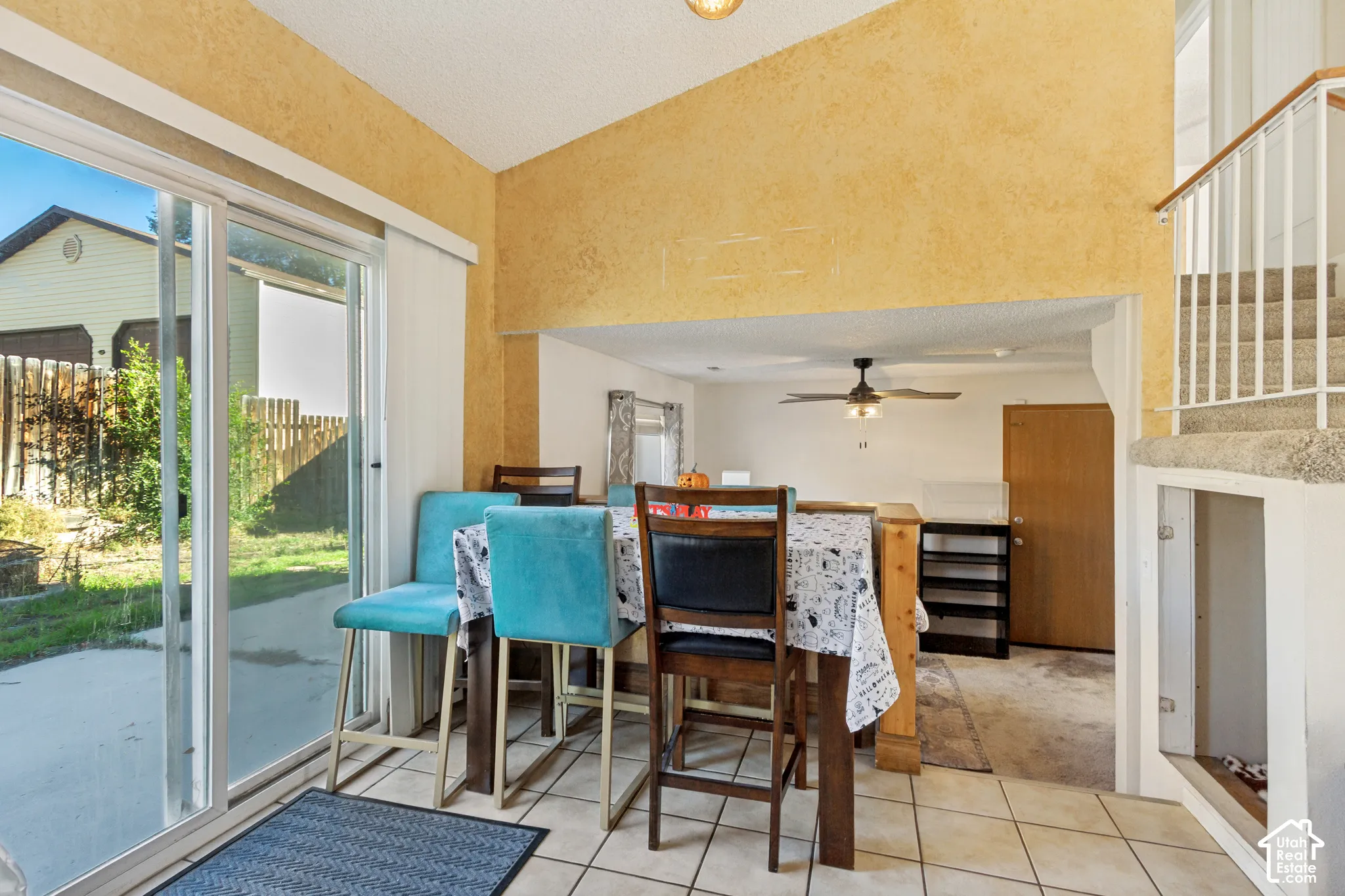 Vaulted ceilings with recessed lighting, tile flooring, sliding glass door with exterior access, and a metal handrail staircase