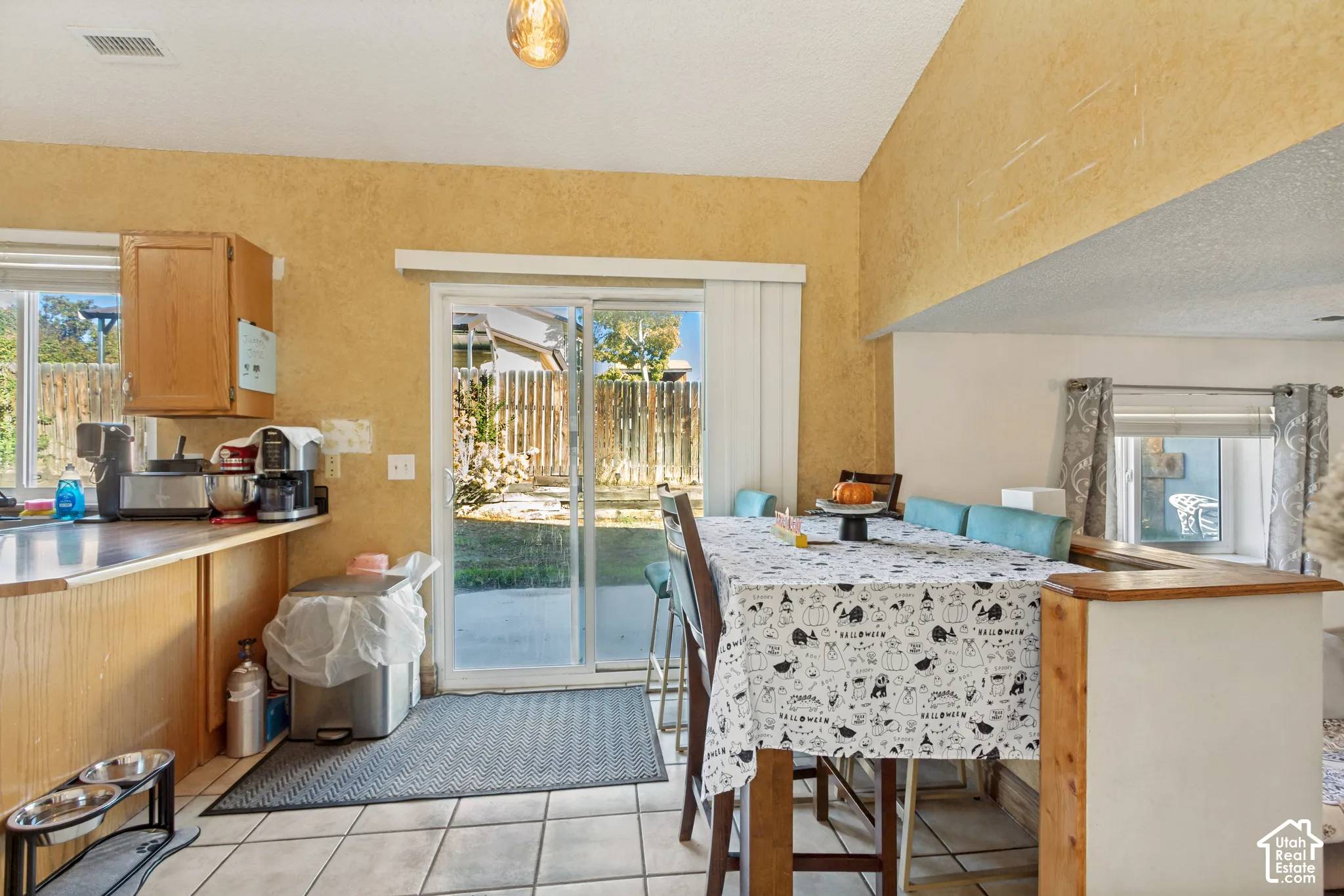 Kitchen area featuring a peninsula, wood cabinetry, tile flooring, vaulted ceiling, and sliding glass patio door