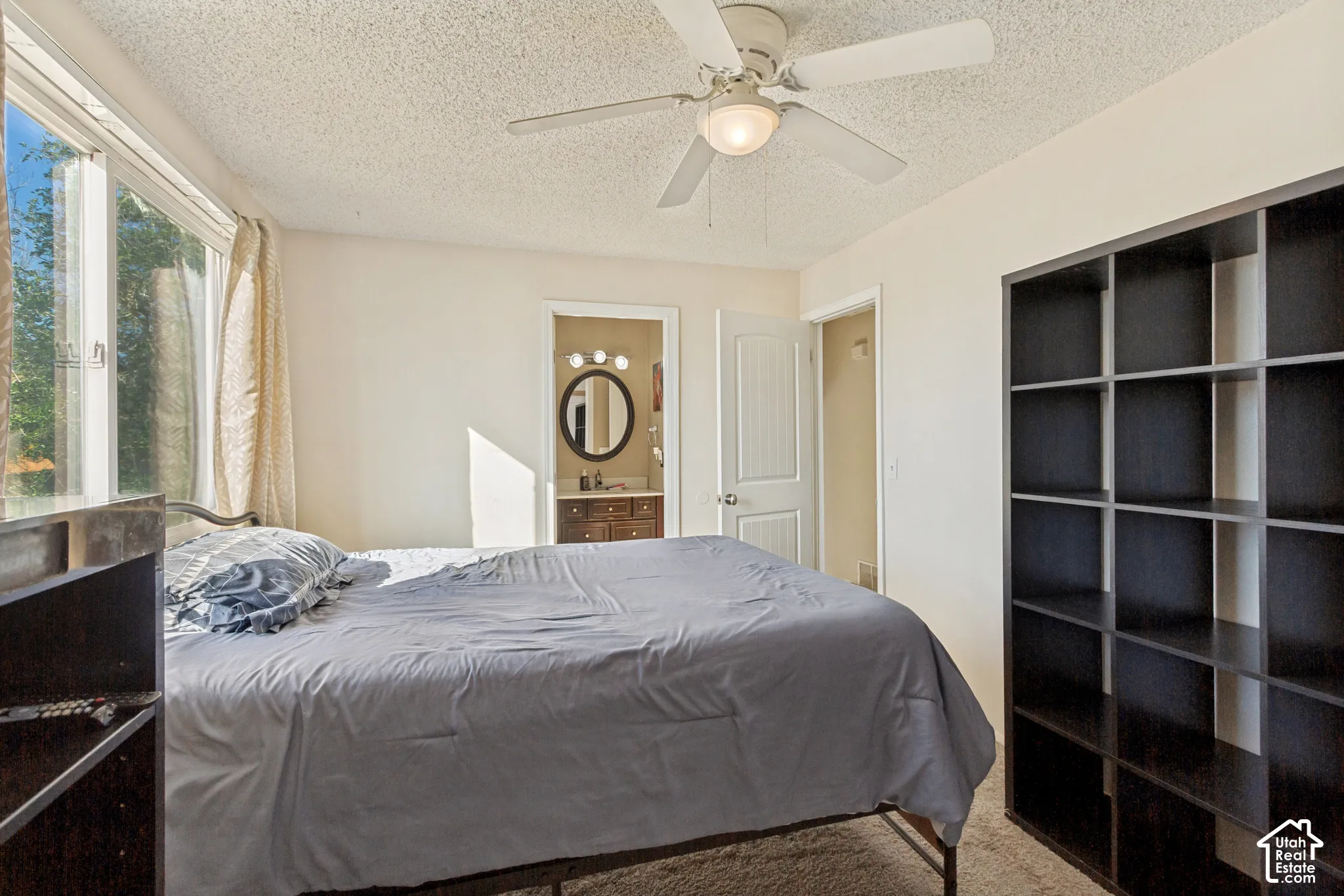 Room featuring large window, ceiling fan with integrated lighting, neutral wall paint, and carpeting