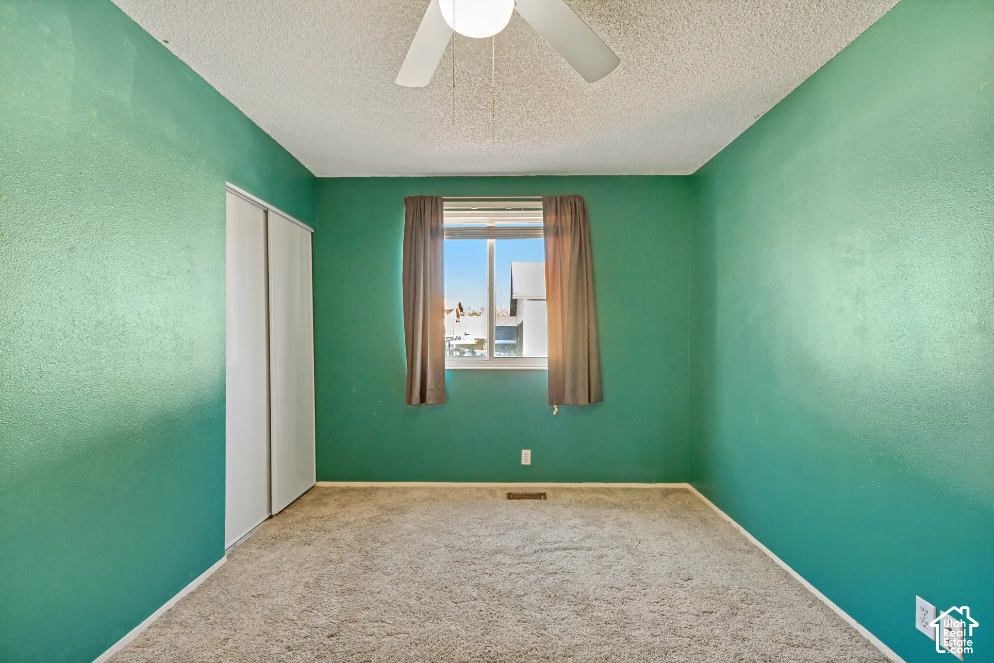 Room featuring wall-to-wall carpeting, dual-panel sliding closet doors, and a ceiling-mounted light fixture with integrated fan