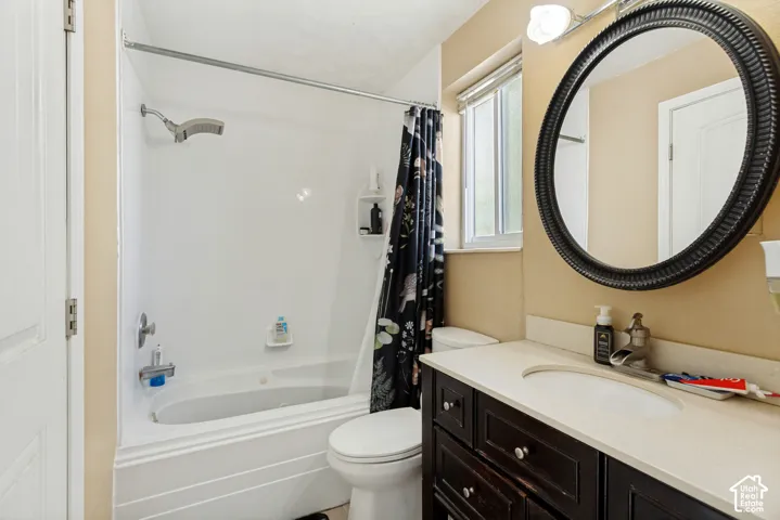 Bathroom featuring a dark-finish vanity with a light-toned countertop, integrated basin, wall-mounted oval mirror, and a tub-shower combination with a molded surround