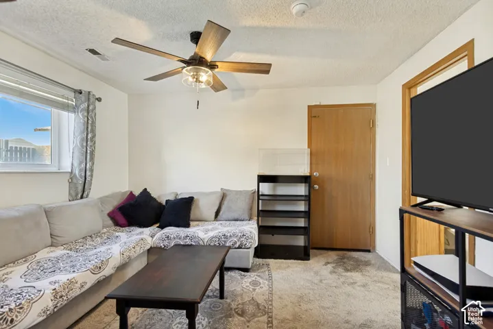 Room featuring a central ceiling fan with integrated lighting, a sliding window with horizontal blinds, and a wood-finish interior door