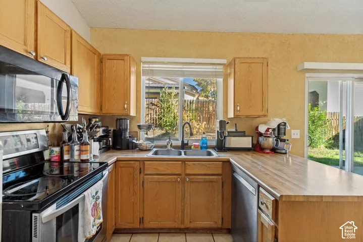 Kitchen featuring wood cabinetry, laminate countertops, double-basin stainless steel sink, over-the-range microwave, and a sliding glass door