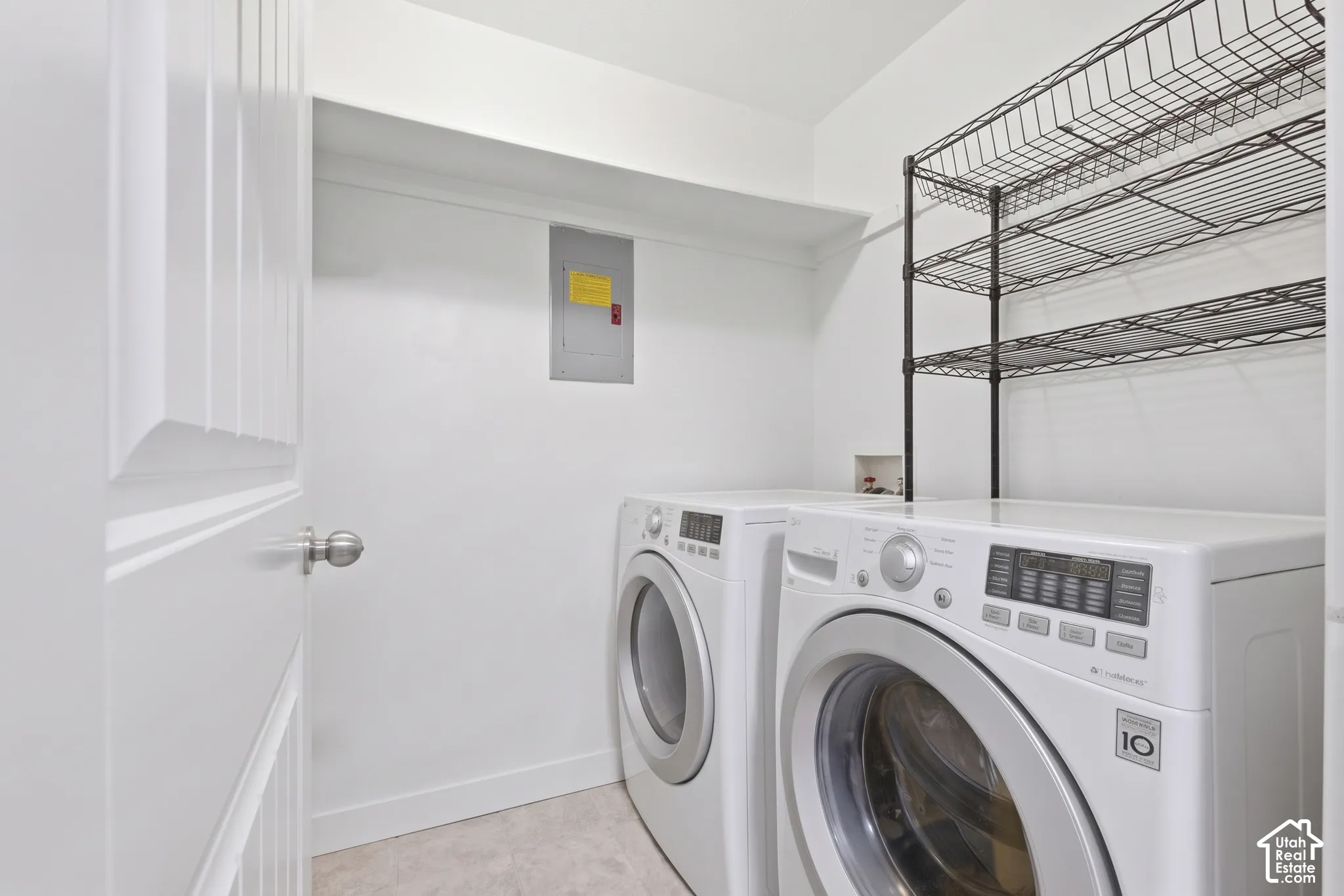 Dedicated laundry area featuring white walls, overhead shelving, and a built-in electrical panel