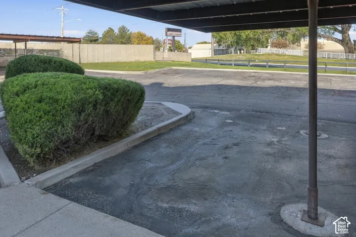 Covered parking structure featuring asphalt paving, concrete curbing, and manicured shrubbery