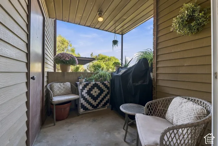 Covered balcony featuring horizontal siding, a concrete floor, and an overhead light fixture