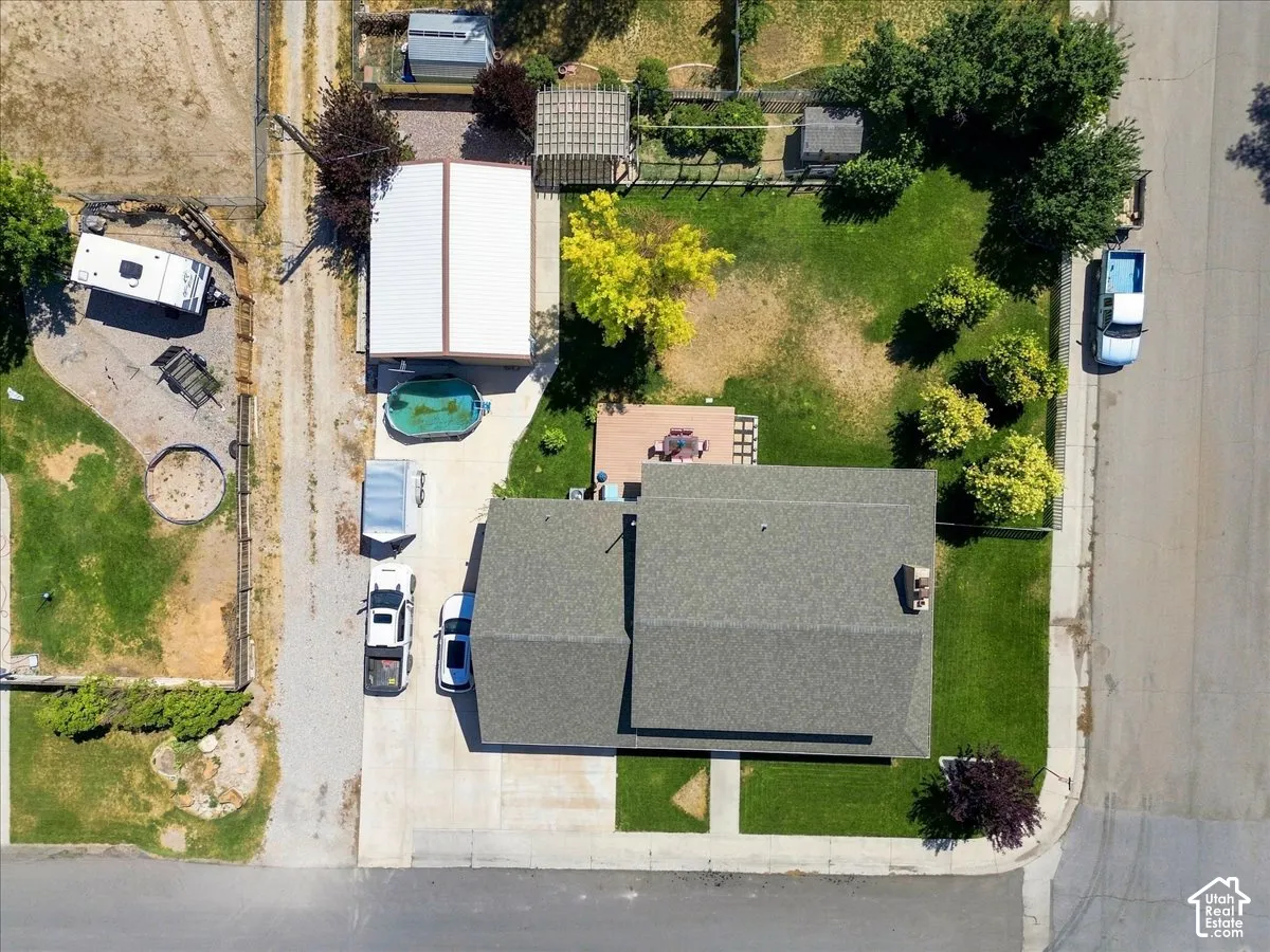 Aerial view of property featuring a detached metal-sided outbuilding, a concrete driveway, a wood-surfaced deck, and mature landscaping