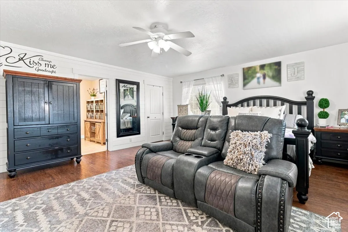 Horizontal shiplap wall paneling, wood-finish flooring, and a multi-blade ceiling fan with integrated lighting