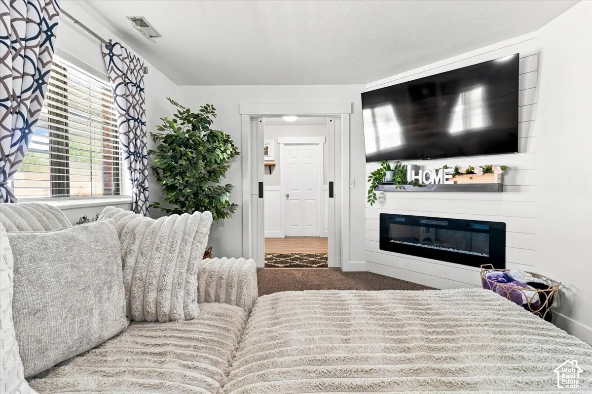 White shiplap accent wall featuring a built-in horizontal electric fireplace, floating mantel, and interior sliding barn door with matte black hardware