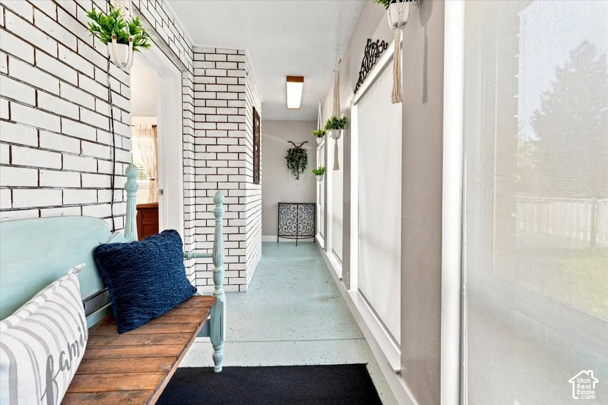 Enclosed sunroom featuring white painted brick walls, large windows, and solid-surface flooring