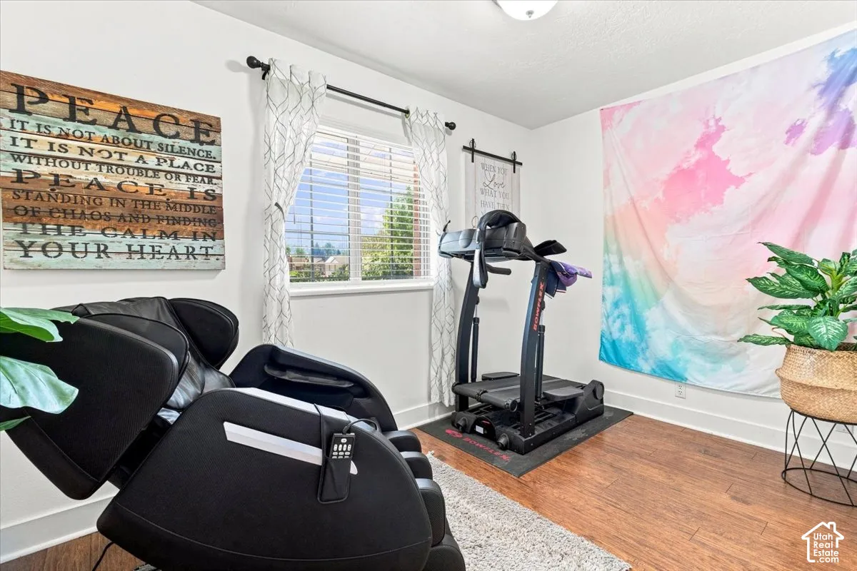 Room featuring wood-finish flooring, a neutral color palette, and a window with horizontal blinds