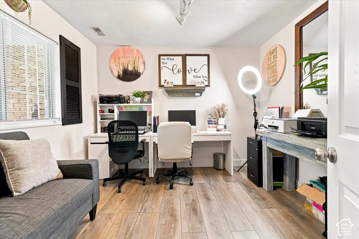 Room featuring wood-finish flooring, a multi-pane window with louvered shutters, and ceiling-mounted track lighting
