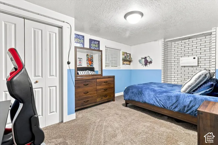 Interior space featuring a white painted brick masonry wall, dual-panel closet doors, neutral wall-to-wall carpeting, and a flush-mount ceiling light fixture